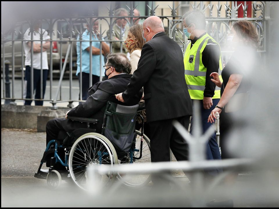 Helped: Brian Cowen is wheeled to the church for the service