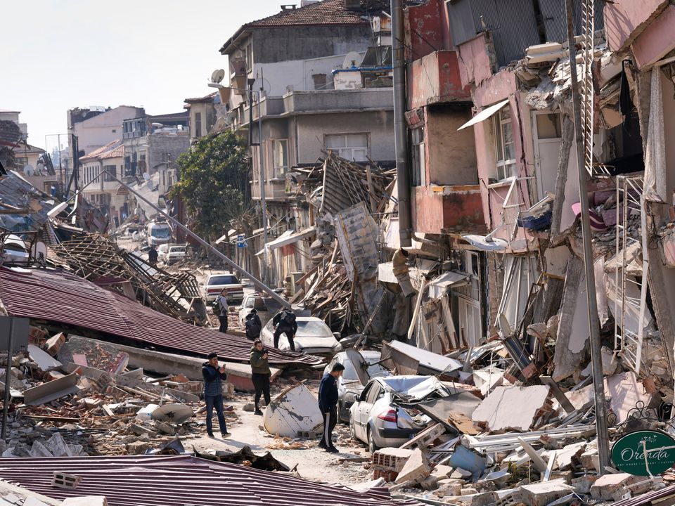 People walk over debris of collapsed buildings in Hatay, Turkey, Saturday, Feb. 11, 2023. Emergency crews made a series of dramatic rescues in Turkey on Friday and Saturday, pulling several people from the rubble days after a catastrophic 7.8-magnitude earthquake killed thousands in Turkey and Syria. (AP Photo/Hussein Malla)
