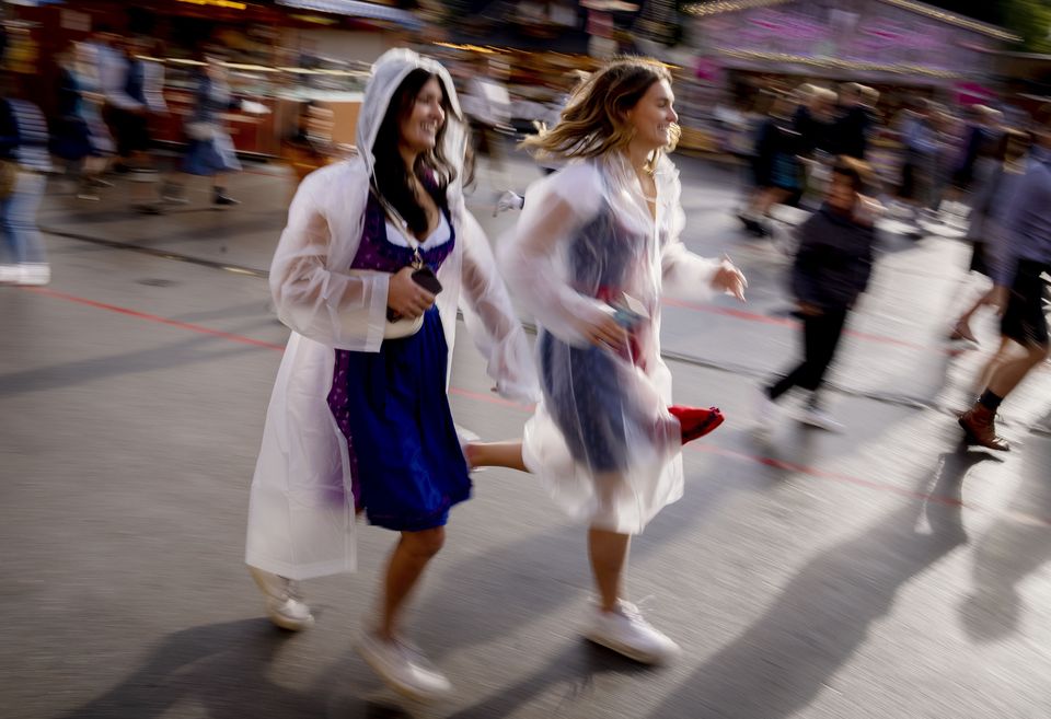 Visitors run onto the festival ground on the opening day of the 187th Oktoberfest beer festival in Munich, Germany, Saturday, Sept. 17, 2022. Oktoberfest is back in Germany after two years of pandemic cancellation, the same bicep-challenging beer mugs, fat-dripping pork knuckles, pretzels the size of dinner plates, men in leather shorts and women in cleavage-baring traditional dresses. (AP Photo/Michael Probst)