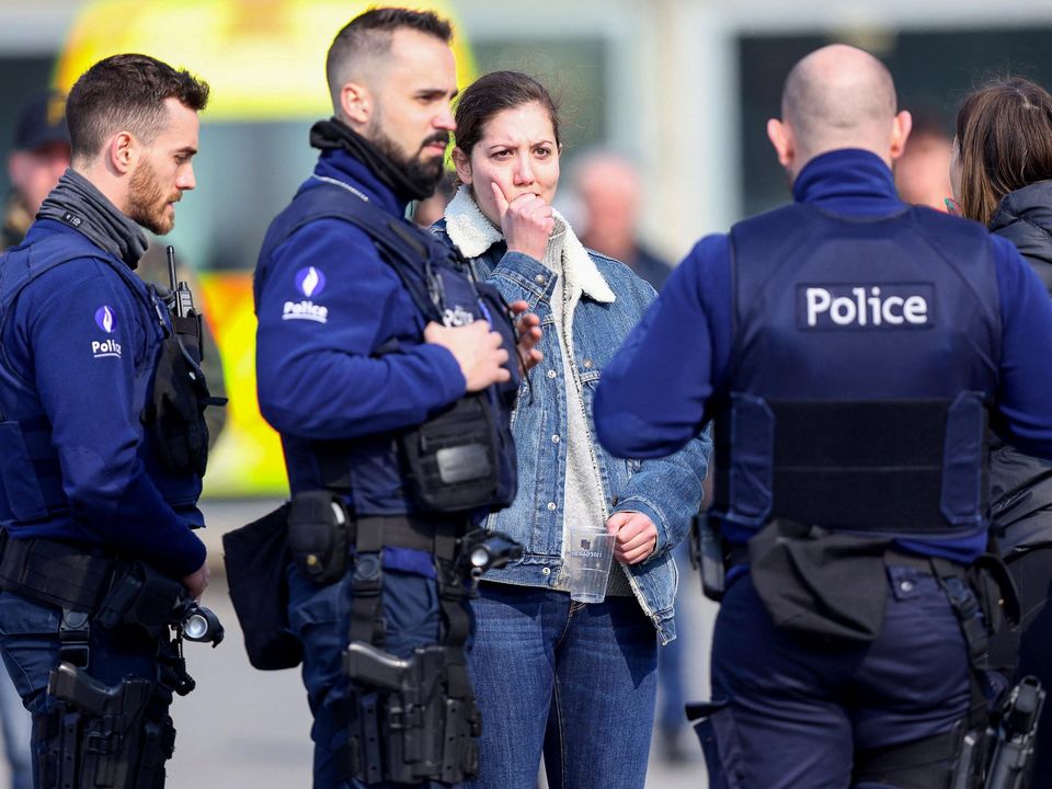 A woman reacts as police officers keep guard after a vehicle drove into a group of Belgian carnival performers who were preparing for a parade in the village of Strepy-Bracquegnies, Belgium March 20, 2022. REUTERS/Johanna Geron
