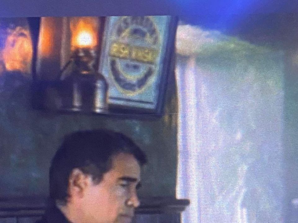 Colin Farrell's character in front of the Irish Whisky sign
