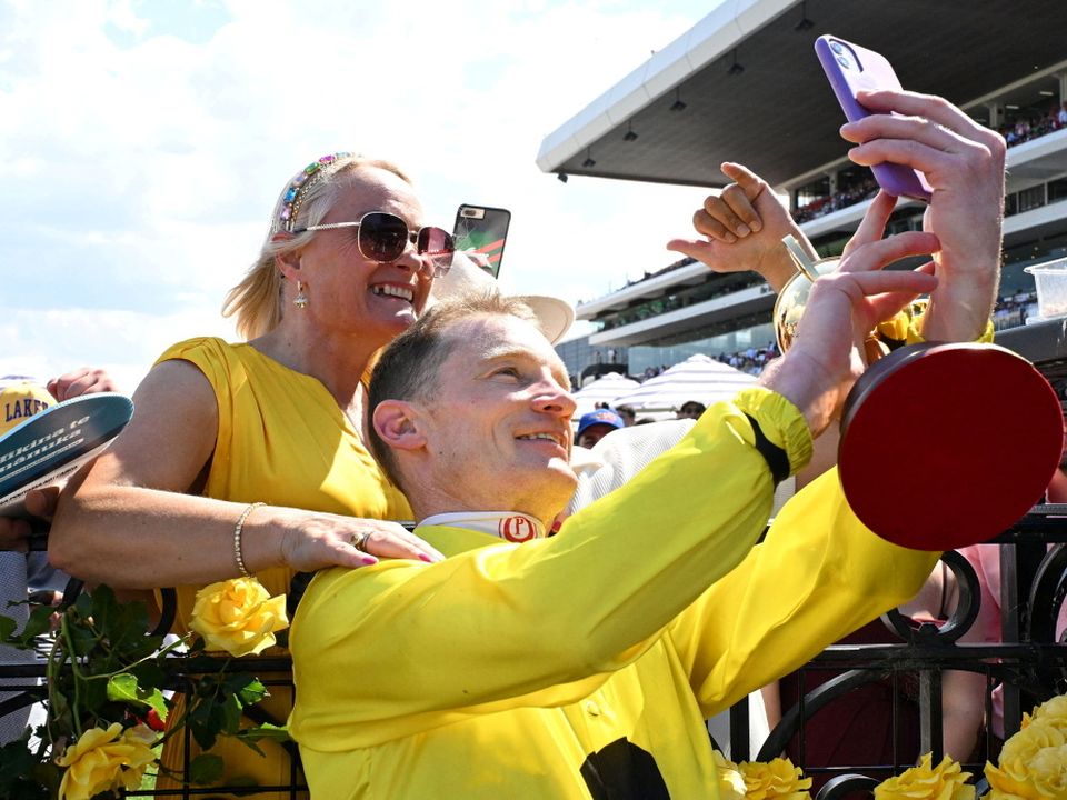 Jockey Mark Zahra takes a photograph with a spectator after riding Without a Fight to victory at the 2023 Melbourne Cup