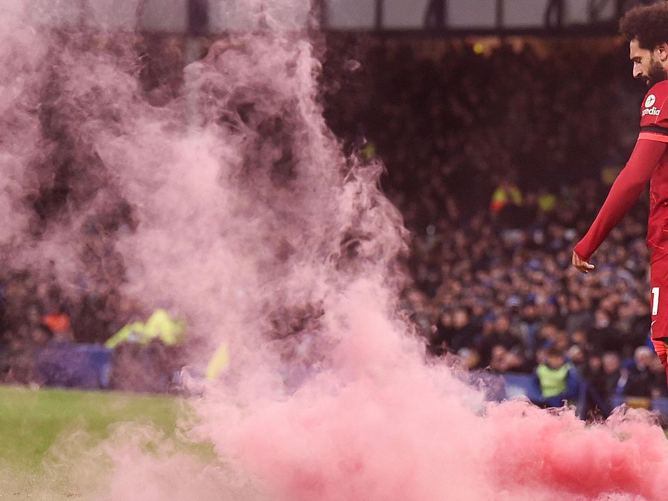 Mo Salah walks past a flare thrown onto the pitch by Liverpool fans at Goodison Park in December. Credit: Getty Images