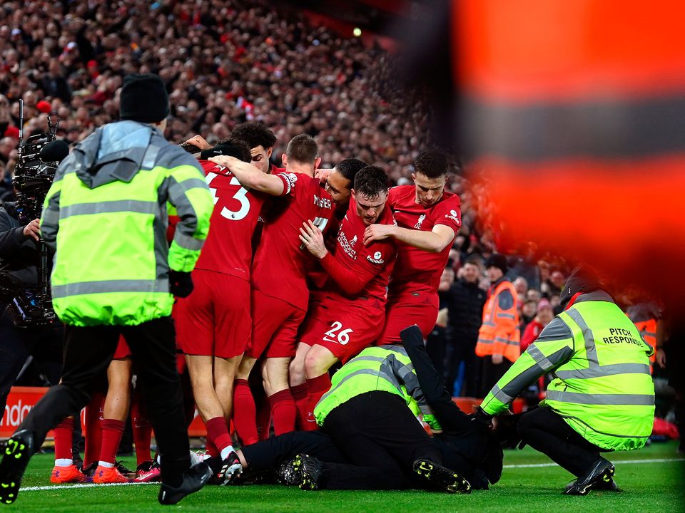 LIVERPOOL, ENGLAND - MARCH 05: A pitch invader is tackled by stewards after colliding with Andrew Robertson of Liverpool as players of Liverpool celebrate after Roberto Firmino of Liverpool ( Obscured ) scores the team's seventh goal during the Premier League match between Liverpool FC and Manchester United at Anfield on March 05, 2023 in Liverpool, England. (Photo by Michael Regan/Getty Images)