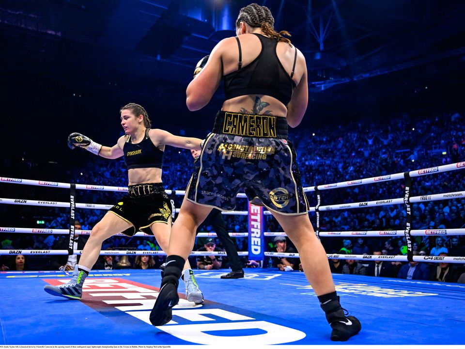 25 November 2023; Katie Taylor, left, is knocked down by Chantelle Cameron in the opening round of their undisputed super lightweight championship bout at the 3Arena in Dublin. Photo by Stephen McCarthy/Sportsfile