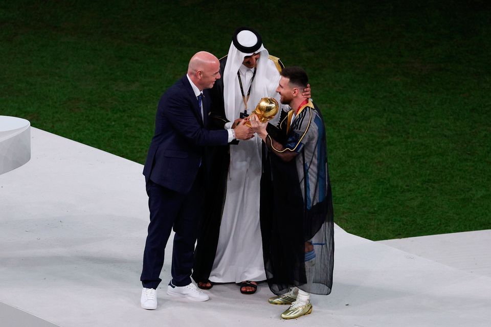 LUSAIL CITY, QATAR - DECEMBER 18: Lionel Messi of Argentina holds the FIFA World Cup Qatar 2022 Winner's Trophy as he interacts with Gianni Infantino, President of FIFA, and Sheikh Tamim bin Hamad Al Thani, Emir of Qatar, during the FIFA World Cup Qatar 2022 Final match between Argentina and France at Lusail Stadium on December 18, 2022 in Lusail City, Qatar. (Photo by Richard Heathcote/Getty Images)