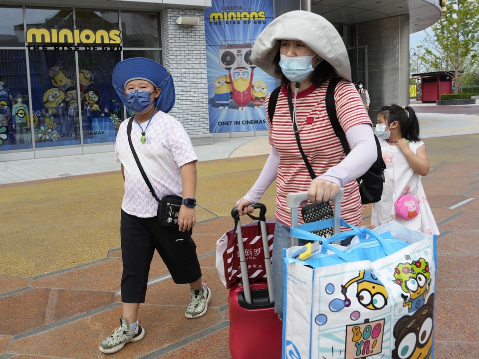 Visitors outside the Universal Studio Beijing theme park pass by a shop selling memorabilia for the latest "Minions: The Rise of Gru" movie in Beijing. (AP Photo/Ng Han Guan)