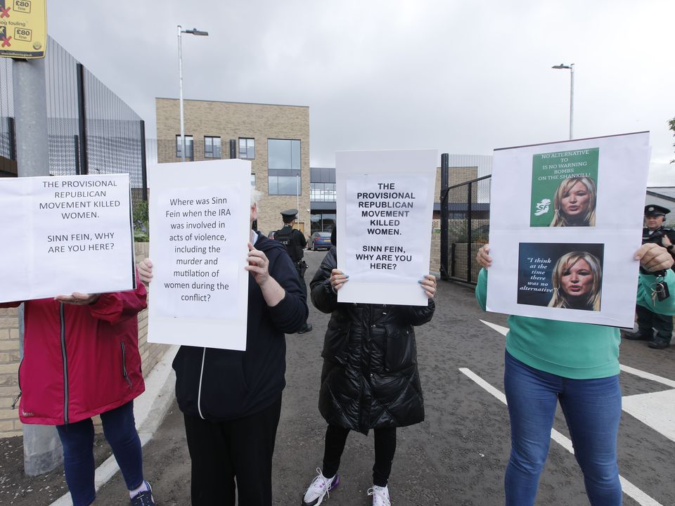 Los manifestantes agitan pancartas frente al Centro de Mujeres Shankill durante una visita de Michelle O'Neill y Emma Little Bingley.