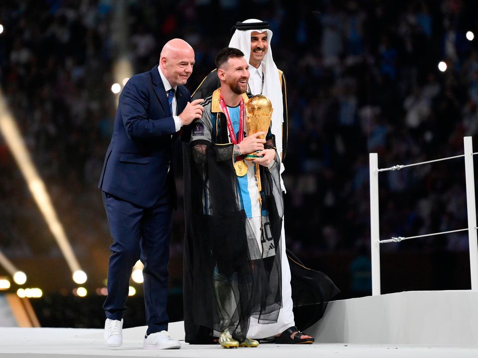 Lionel Messi of Argentina receives the World Cup from Gianni Infantino and Sheikh Tamim bin Hamad Al Thani. Photo by Dan Mullan / Getty