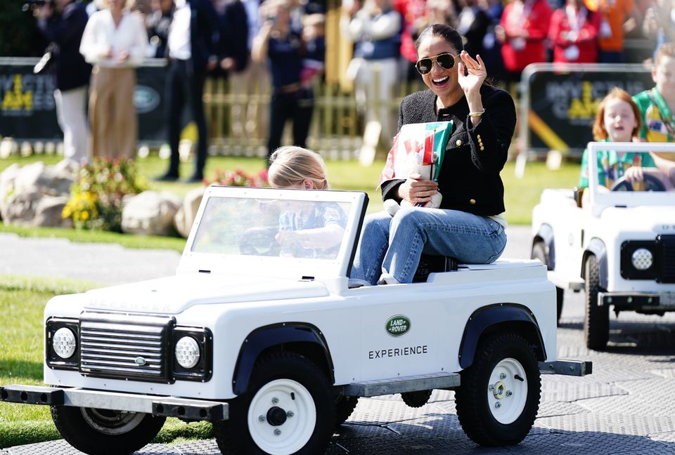 Meghan is driven by a child in a toy Land Rover at the Invictus Games (Aaron Chown/PA)