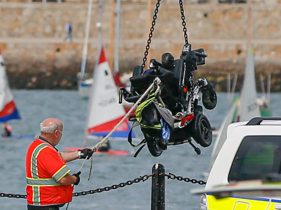 A motorised wheelchair is taken from the water at Dun Laoghaire Harbour today