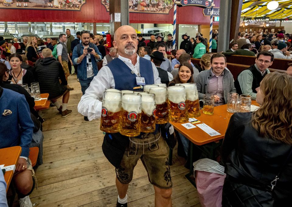 A waiter carries beer in one of the beer tents on the opening day of the 187th Oktoberfest beer festival in Munich, Germany, Saturday, Sept. 17, 2022. Oktoberfest is back in Germany after two years of pandemic cancellations, the same bicep-challenging beer mugs, fat-dripping pork knuckles, pretzels the size of dinner plates, men in leather shorts and women in cleavage-baring traditional dresses. (AP Photo/Michael Probst)