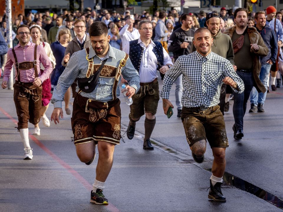 People run onto the festival ground on the opening day of the 187th Oktoberfest beer festival in Munich, Germany, Saturday, Sept. 17, 2022. Oktoberfest is back in Germany after two years of pandemic cancellations, the same bicep-challenging beer mugs, fat-dripping pork knuckles, pretzels the size of dinner plates, men in leather shorts and women in cleavage-baring traditional dresses. (AP Photo/Michael Probst)
