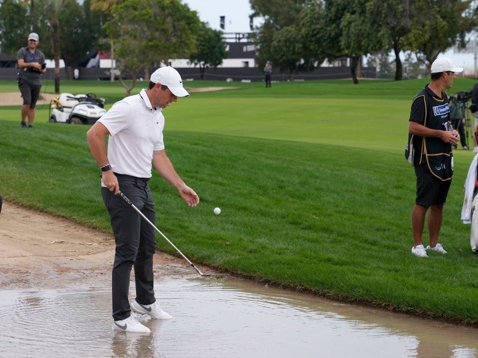 Rory McIlroy retrieves his ball from water on the 10th hole