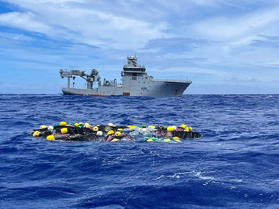 A shipment of cocaine floats on the surface of the Pacific Ocean with Royal New Zealand Navy vessel HMNZS Manawanui behind Photo: NZ Police via AP