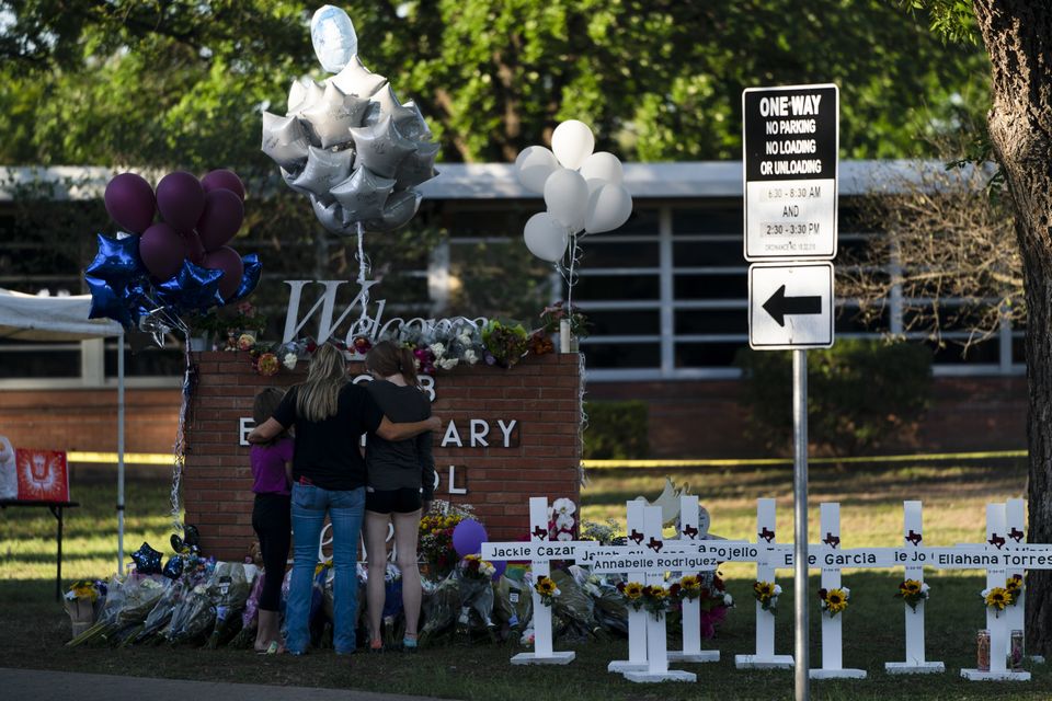 A family pays their respects next to crosses bearing the names of Tuesday’s shooting victims at Robb Elementary School in Uvalde (Jae C Hong/AP)