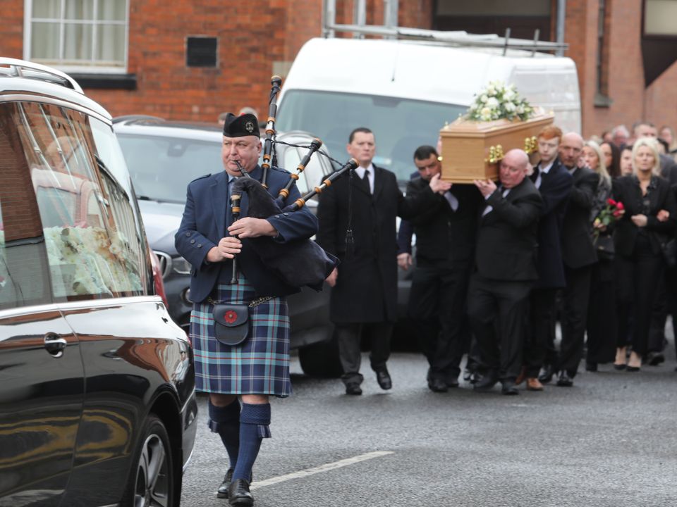 A bagpiper leads the funeral procession in Belfast today