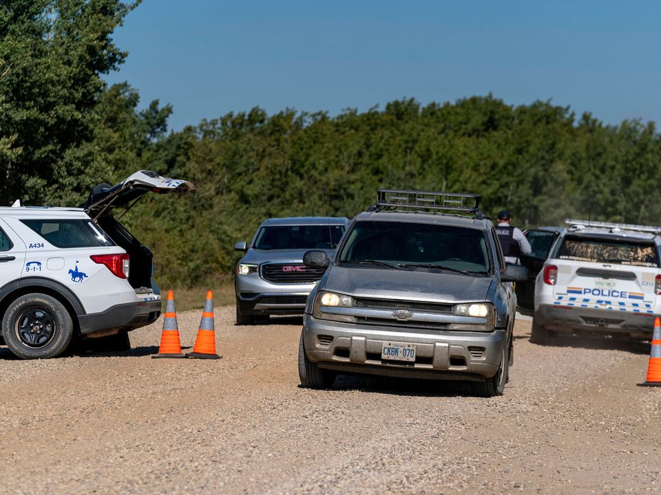 Cars drive out of a police roadblock on the James Smith Cree First Nation reservation in Saskatchewan