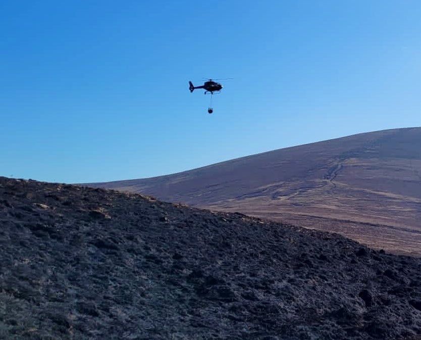 A helicopter dropping super-sized buckets of water on the blaze to douse flames and hot spots.