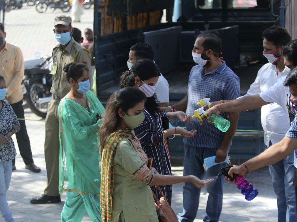 Volunteers offer hand sanitiser to devotees arriving at a temple in Jammu, India (Channi Anand/AP)