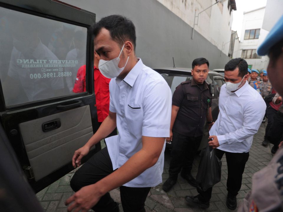 Police officers Bambang Sidik Achmadi, left, and Wahyu Setyo Pranoto are escorted by security guards to a prosecutors' van after their sentencing hearing at a district court in Surabaya, Indonesia. The Indonesian court acquitted Achmadi and Pranoto.