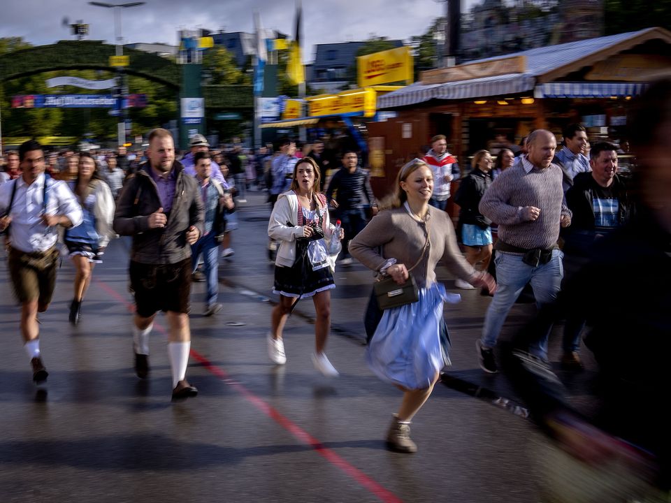 Visitors run onto the festival ground on the opening day of the 187th Oktoberfest beer festival in Munich, Germany, Saturday, Sept. 17, 2022. Oktoberfest is back in Germany after two years of pandemic cancellation, the same bicep-challenging beer mugs, fat-dripping pork knuckles, pretzels the size of dinner plates, men in leather shorts and women in cleavage-baring traditional dresses. (AP Photo/Michael Probst)