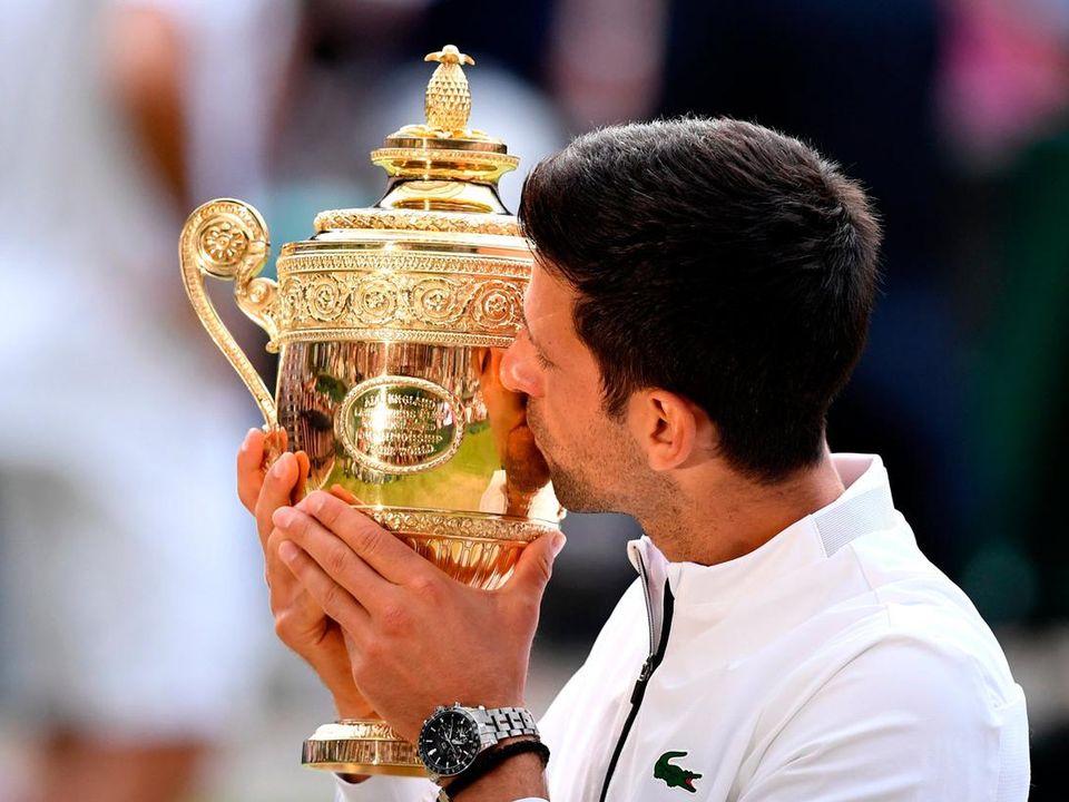 Novak Djokovic of Serbia kisses the trophy after one of his Wimbledon triumphs. (Photo by Matthias Hangst/Getty Images)