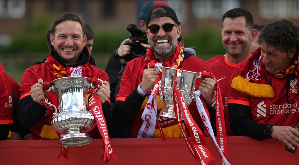 Liverpool's assistant manager Pepikn Lijnders holds the FA cup Trophy and Liverpool's German manager Jurgen Klopp holds the League cup Trophy as they celebrate from an open-top bus during a parade through the streets of Liverpool
