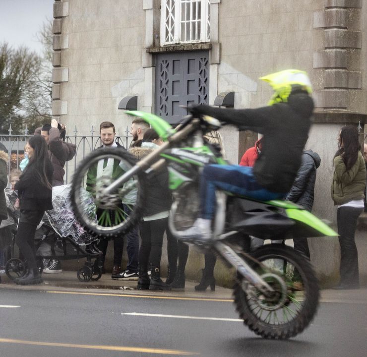 A motorcyclist performs wheelies outside the church as Damien Galvin is laid to rest