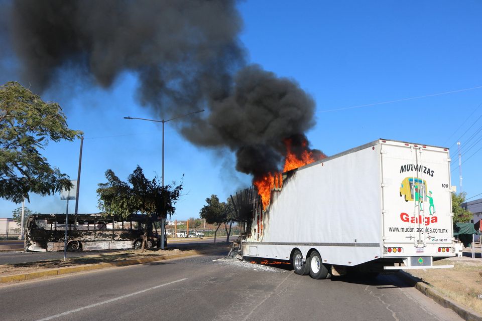 Burnt wreckage of a bus and a burning truck, set on fire following the detention of Ovidio Guzman in Culiacan, Mexico. Photo: Reuters