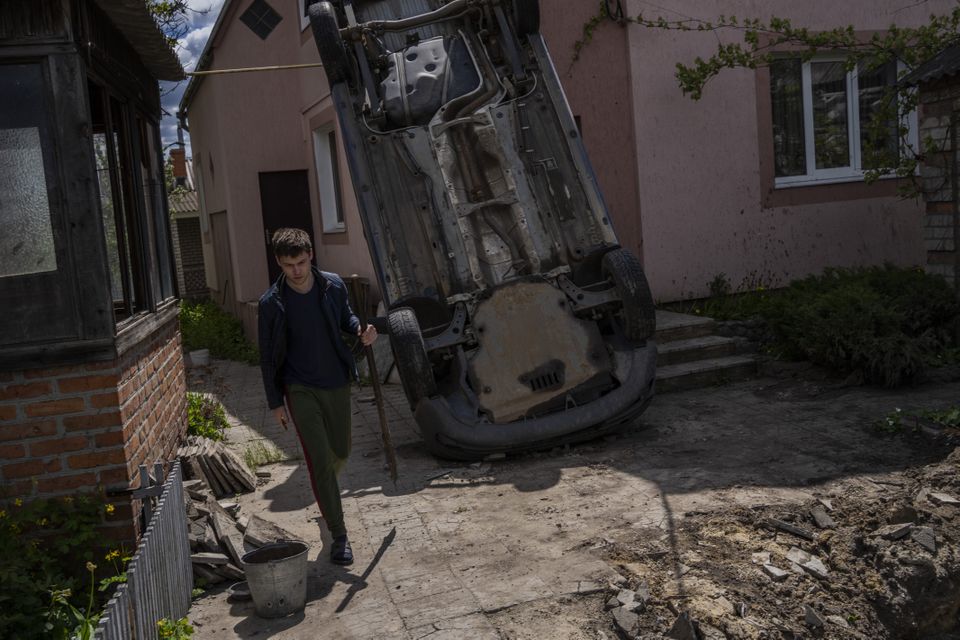 A resident carries a shovel to clear the rubble from his house damaged during a shelling in Kharkiv (AP Photo/Bernat Armangue)
