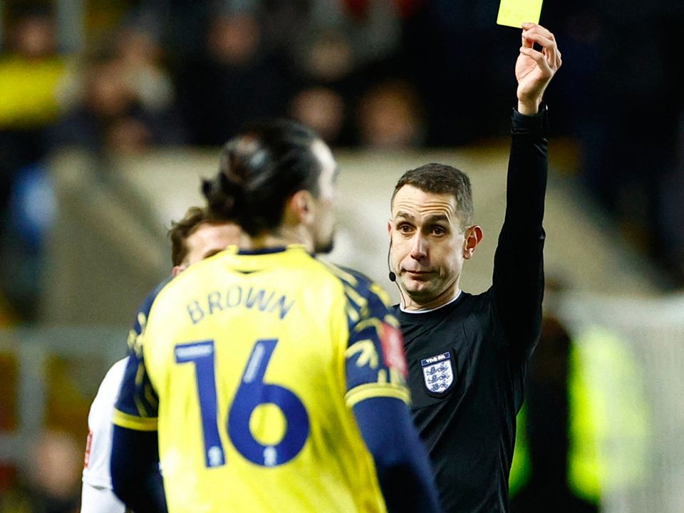 Oxford United's Ciaron Brown is shown a yellow card by referee David Coote on Monday night.