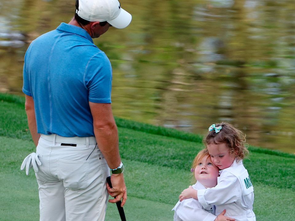 Rory McIlroy looks on as Ivy Lowry hugs Poppy McIlroy on the ninth green