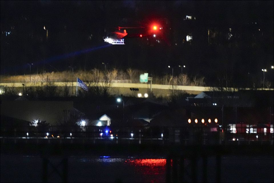 A helicopter uses its searchlight as it flies above the Potomac River near Ronald Reagan Washington National Airport (Alex Brandon/AP)