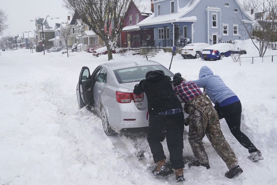 Neighbours help push a motorist stuck in the snow in Buffalo, N.Y., on Monday, Dec. 26, 2022. (Derek Gee/The Buffalo News via AP)