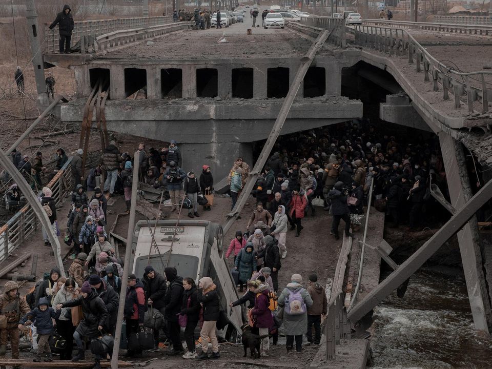 People cross a destroyed bridge as they try to leave the city of Irpin, in the Kyiv region