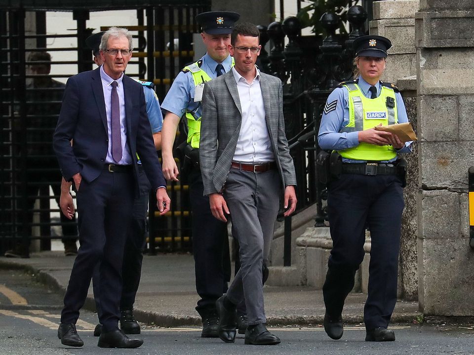 Enoch Burke is brought into the Four Courts by gardaí, accompanied by his father, Sean Burke (left). Photo: Collins Courts