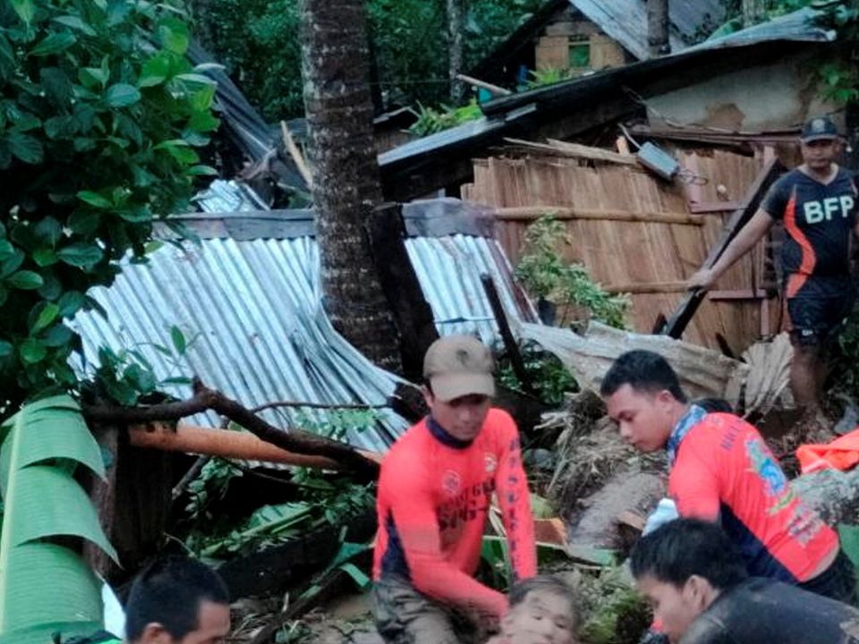Rescue personnel assist a woman amidst flooding