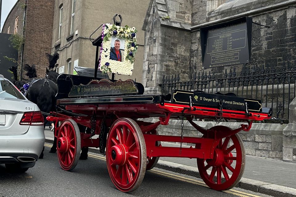 A horse-drawn carriage carries a floral tribute to Martin