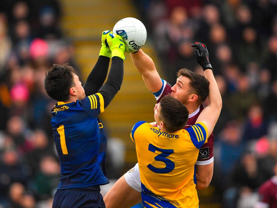 Roscommon goalkeeper Conor Carroll punches a ball away despite the challenge from Damien Comer of Galway as Conor Daly of Roscommon watches on  Ray Ryan/Sportsfile