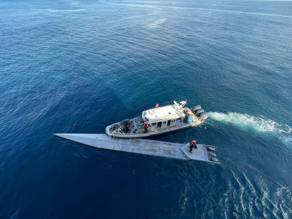 Authorities are seen beside the advanced looking submarine in the Pacific, which may have been constructed in the jungle.