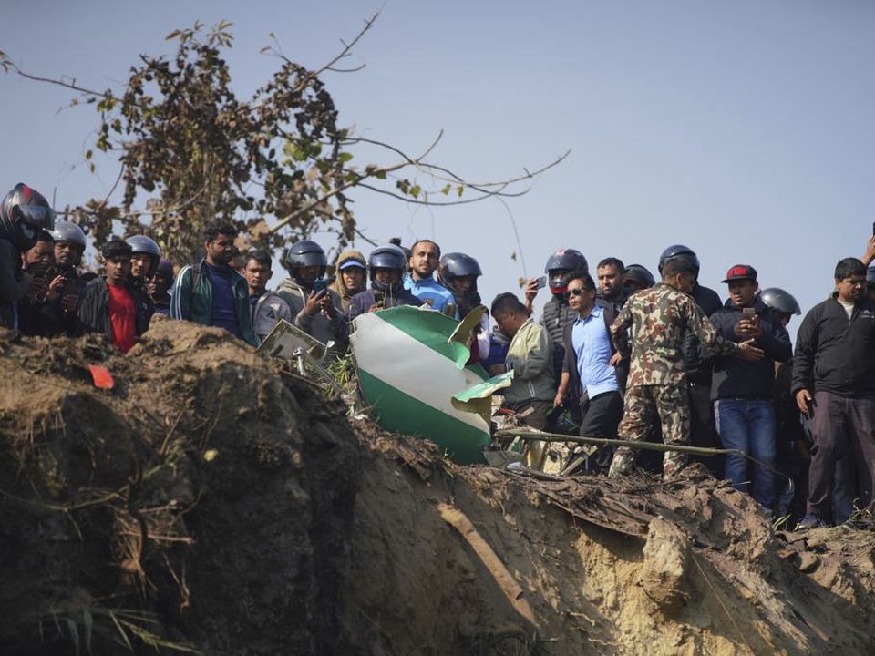 Locals watch the wreckage of a passenger plane in Pokhara, Nepal, Sunday, Jan.15, 2023. A passenger plane with 72 people on board has crashed near Pokhara International Airport in Nepal, the daily newspaper Kathmandu Post reports. The plane was carrying 68 passengers and four crew members. (AP Photo/Yunish Gurung)