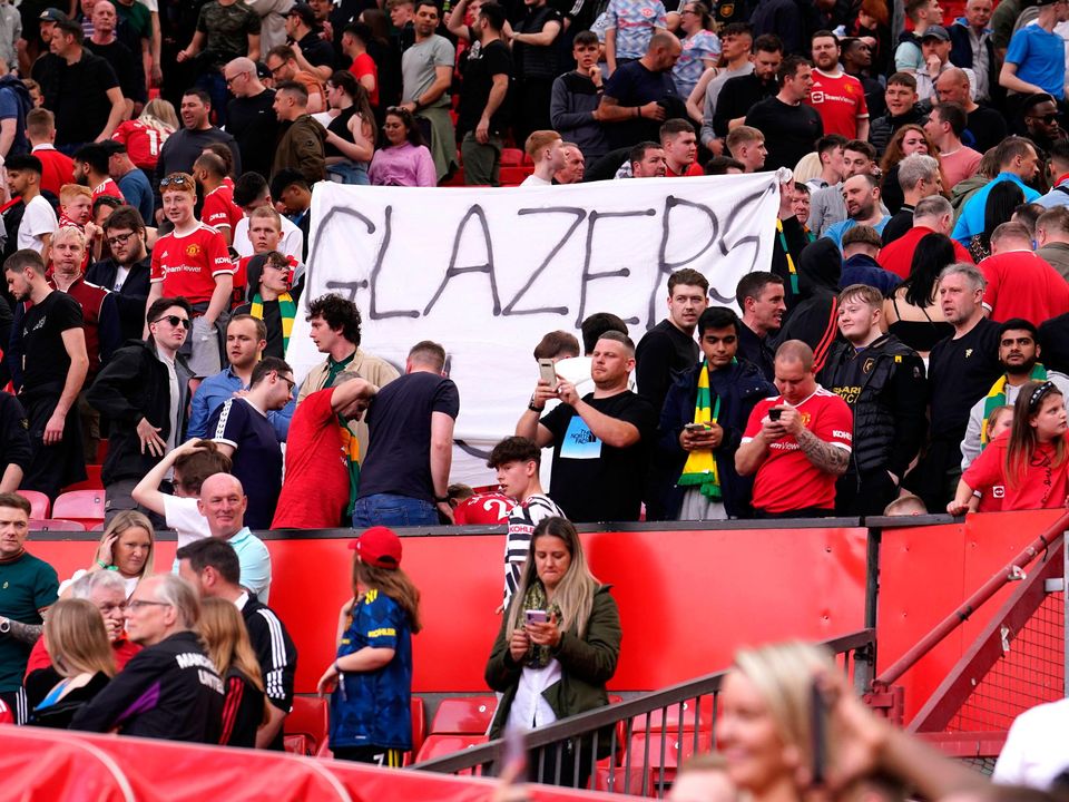 Manchester United fans in the stands wave a 'Glazers Out' banner, protesting the team's ownership at Old Trafford.