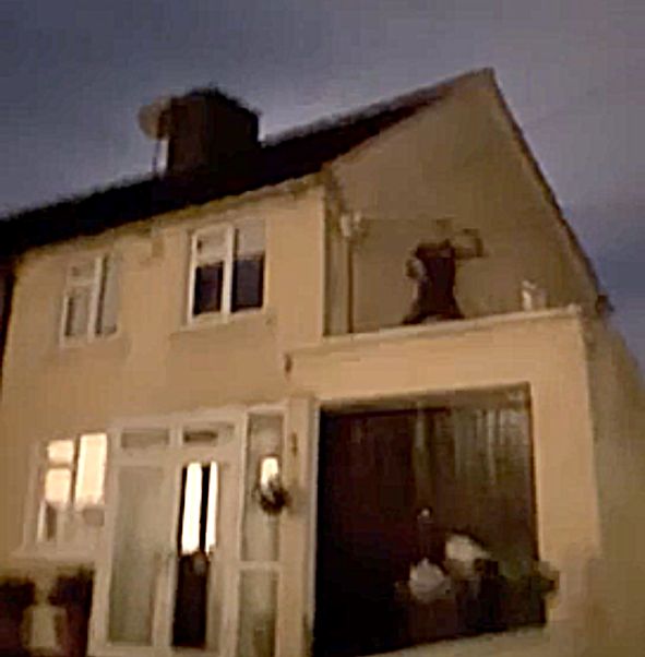 The man on the roof is seen getting ready to throw something as a crowd of women below hurling abuse at him