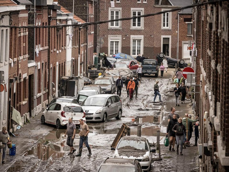 People walk through a damaged street after flooding in Chenee, Province of Liege, Belgium, Friday July 16, 2021. Severe flooding in Germany and Belgium has turned streams and streets into raging torrents that have swept away cars and caused houses to collapse. (AP Photo/Valentin Bianchi)