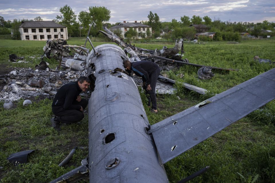 Oleksiy Polyakov and Roman Voitko check the remains of a destroyed Russian helicopter lie in a field in the village of Malaya Rohan, hear Kharkiv (AP Photo/Bernat Armangue)