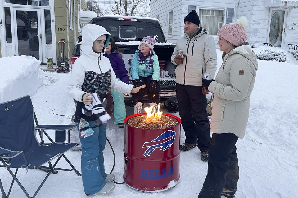 A group gather around a fire pit on Culver Road after clearing snow in Buffalo, N.Y., Monday, Dec. 26, 2022. The region is digging out from a pre-Christmas blizzard that delivered hurricane-force winds and more than 4 feet of snow. (AP Photo/Carolyn Thompson)