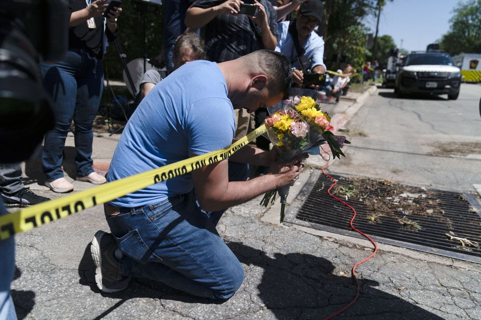 Joseph Avila, left, prays while holding flowers honouring the victims killed in Tuesday’s shooting (Jae C Hong/AP)
