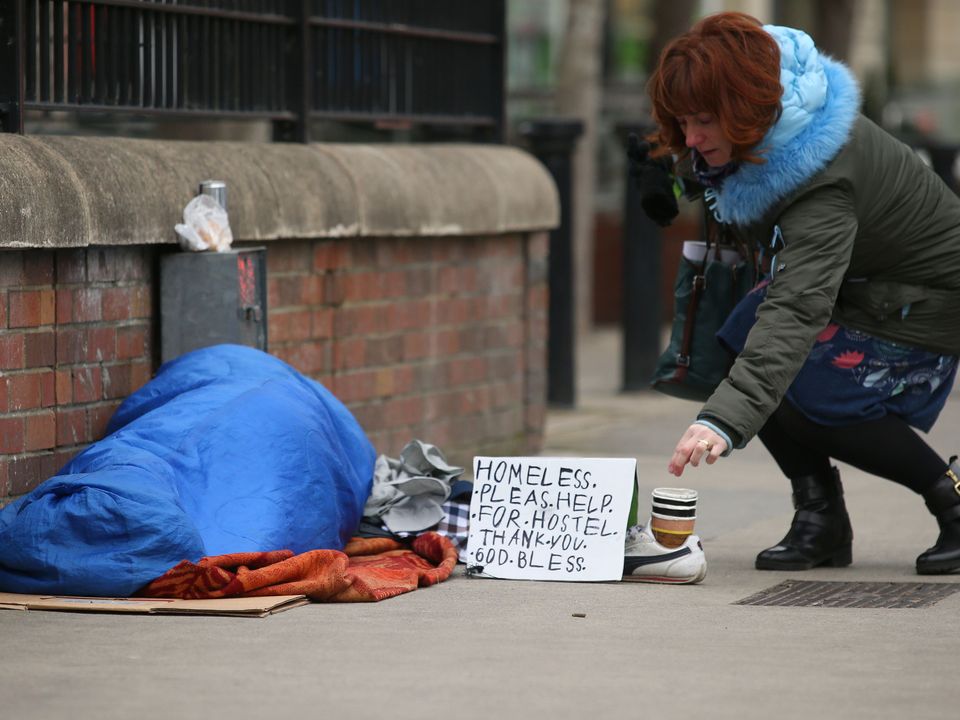 Passerby makes a donation to a homeless person on Dublin’s Waterloo Road. Photo: Damien Eagers