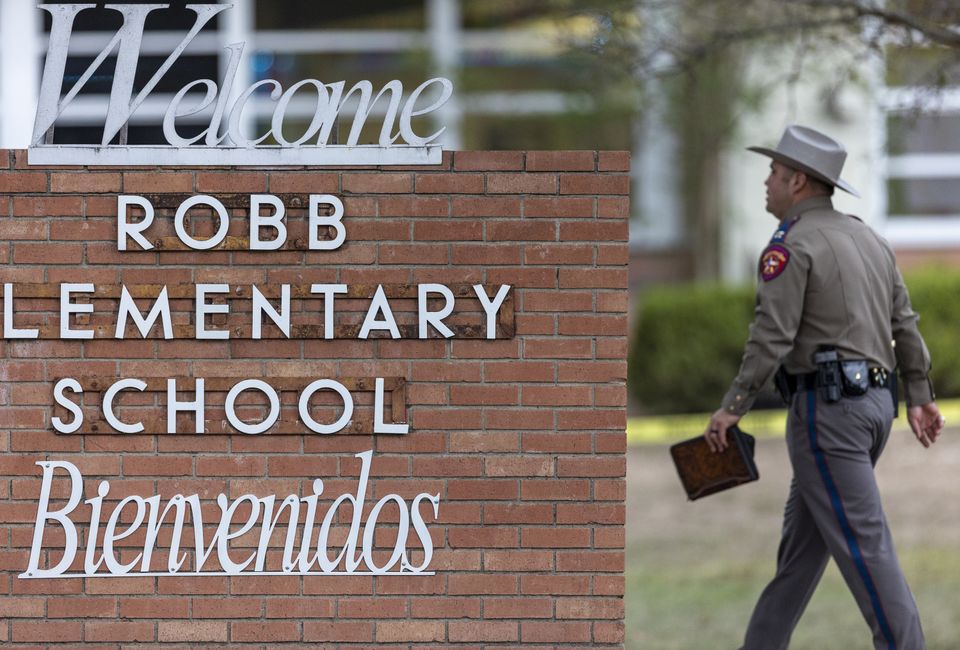 A state trooper walks past the Robb Elementary School sign in Uvalde (William Luther/The San Antonio Express-News via AP)